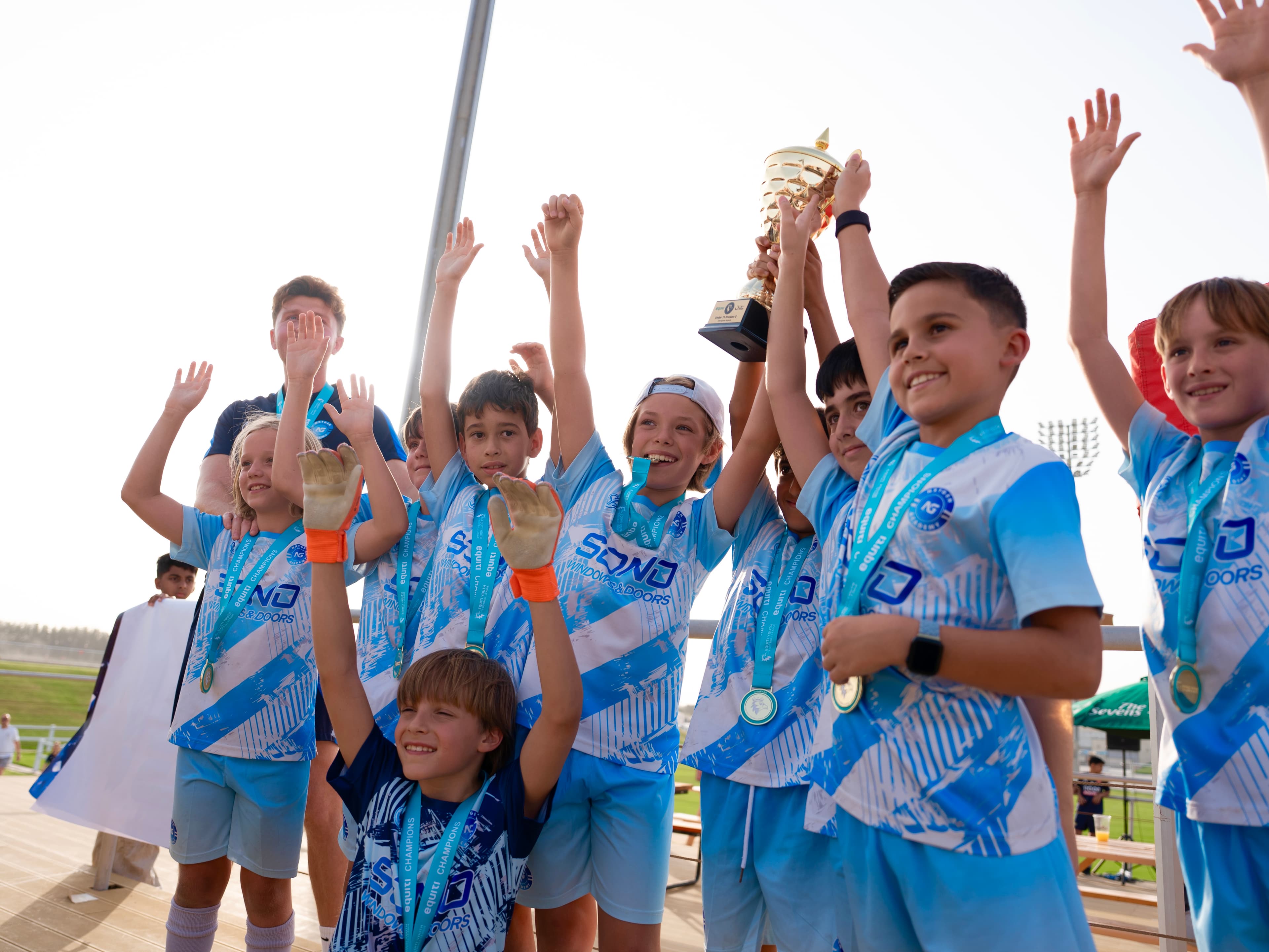 NXTGEN players celebrate together while raising their championship trophy.