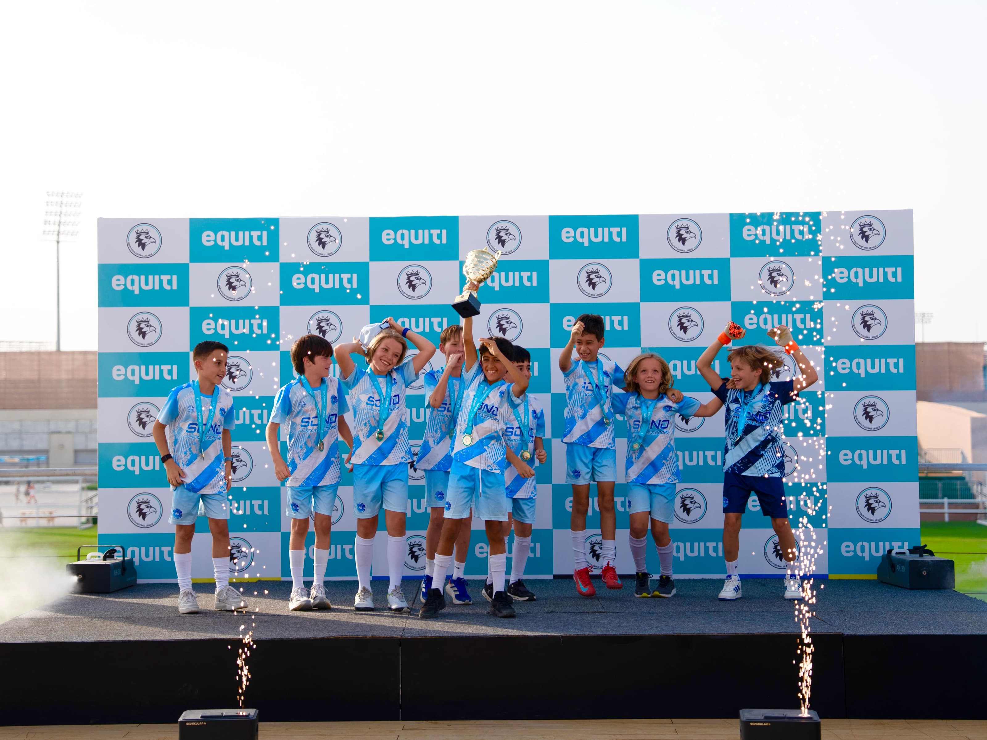 NXTGEN players celebrate together on stage with their championship trophy.