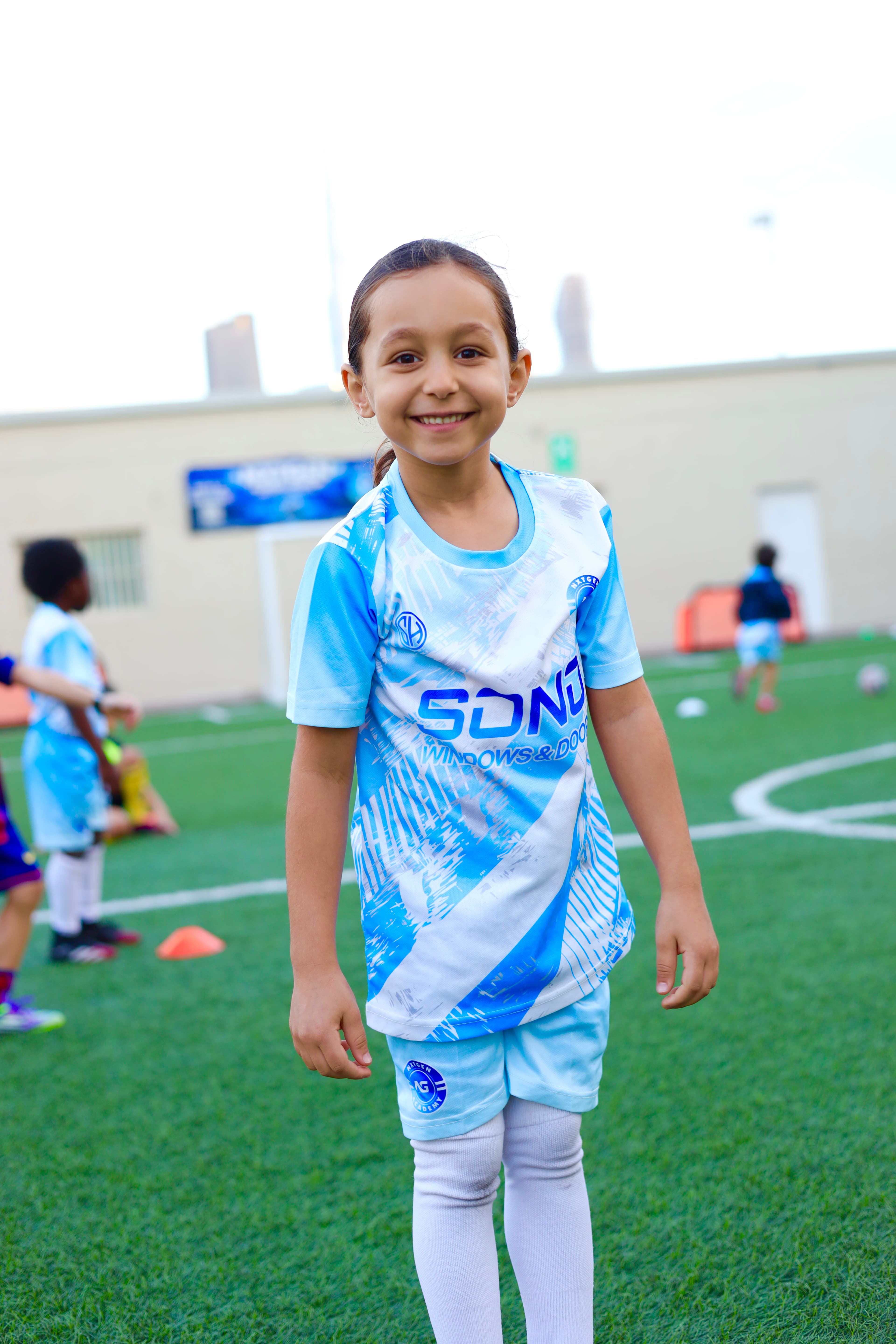 A young NXTGEN Academy player smiles on the training pitch.